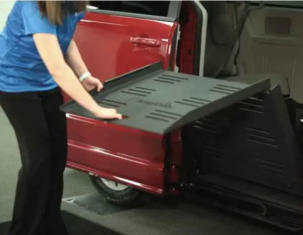 Lady pulling out the wheelchair ramp on a red, manual wheelchair van