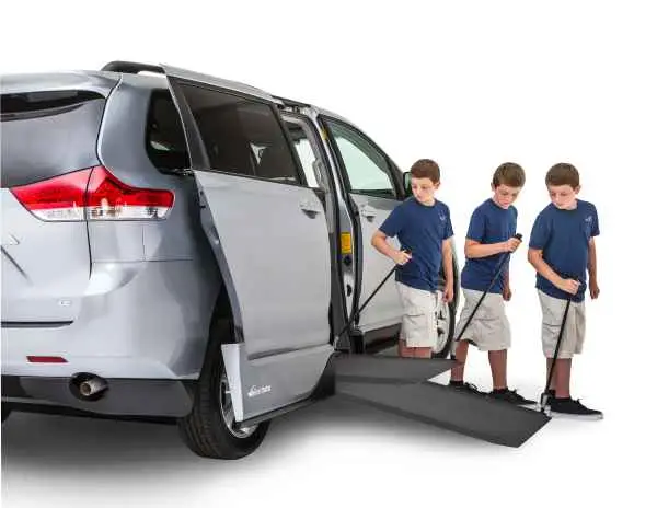 Boy pulling out the manual infloor ramp on silver wheelchair van