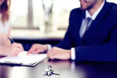 Man in suit at table having woman sign documents for financing