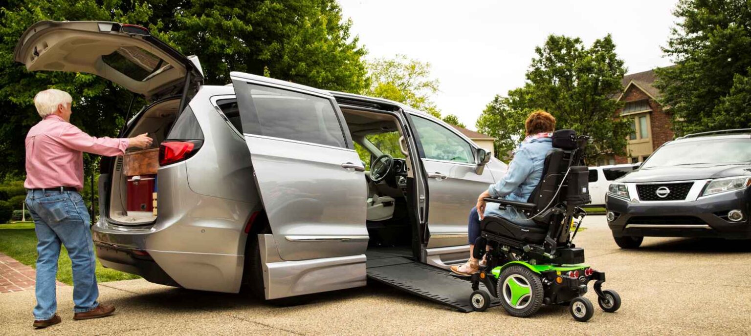 man loading minivan in rear while lady in power wheelchair enters the vehicle using a wheelchair ramp